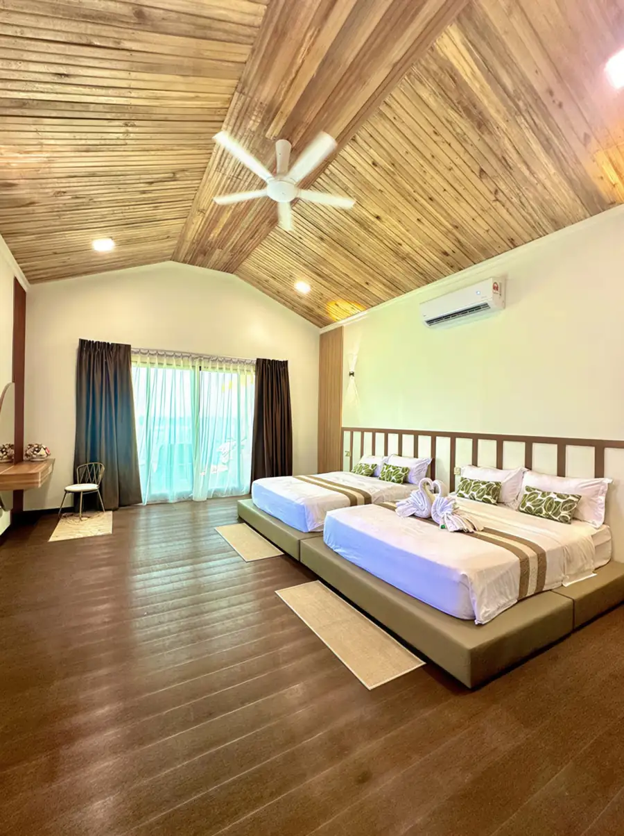 A bright family suite at Dayang Resort Semporna with two large beds, modern white decor, smooth wooden floors, AC and panoramic glass doors opening onto the sea view balcony.