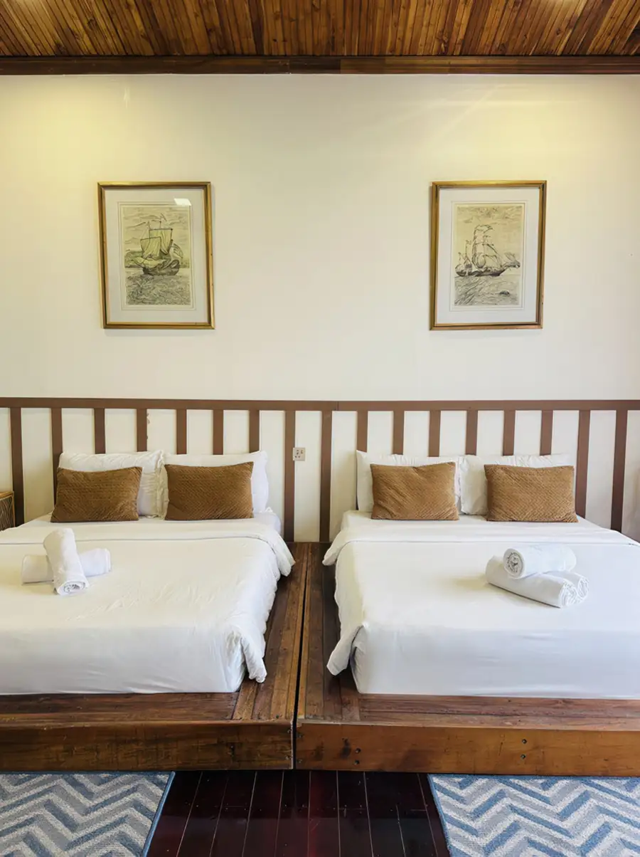 Symmetrical twin beds in a clean white room at Dayang Resort Semporna with ceiling fan and AC.