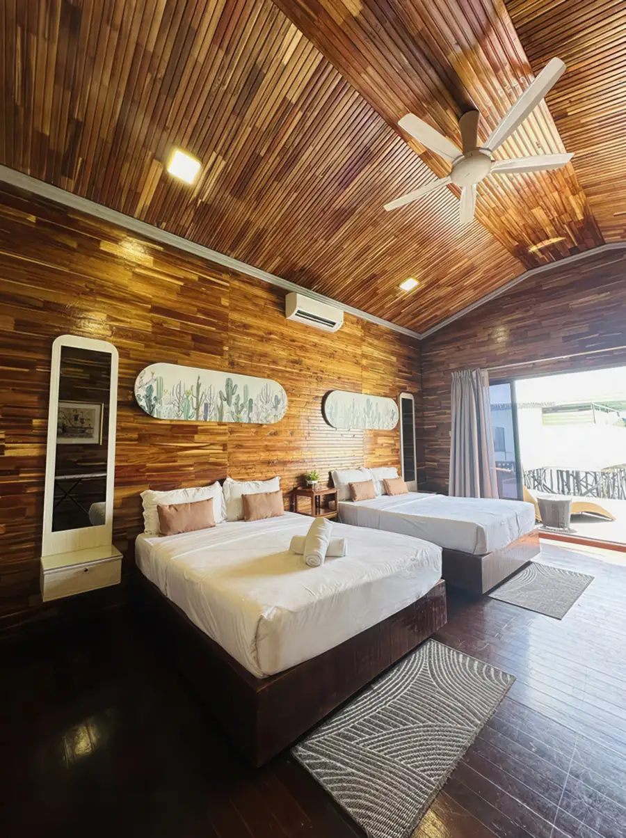 A classic wooden bedroom at Dayang Resort near the Tun Sakaran Marine Park featuring two large beds, large glass doors opening onto the balcony, traditional style wood panel walls with polished wood floors, and A/C.