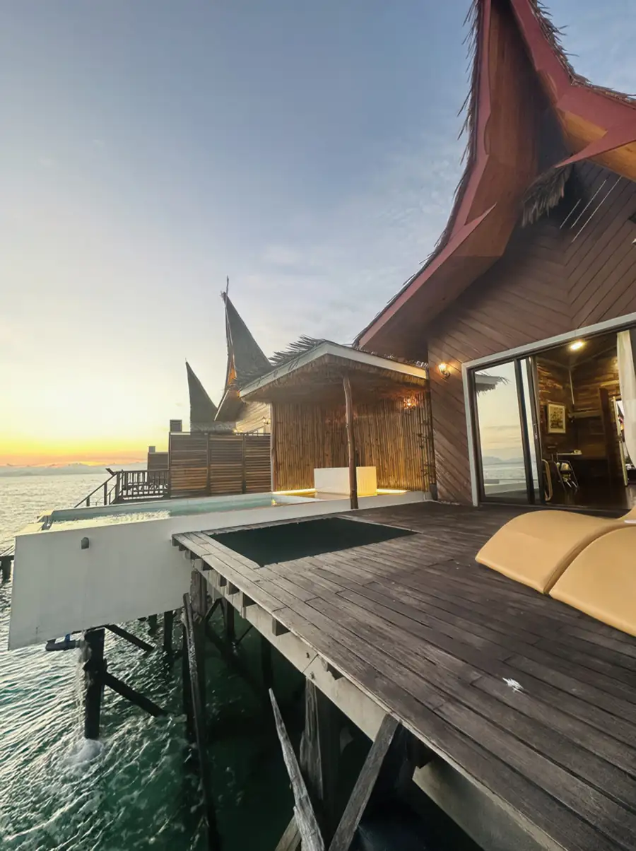A luxury villa in a local style featuring a timber facade, a high-pitched roof, and a wooden deck with sun loungers at Dayang Resort.