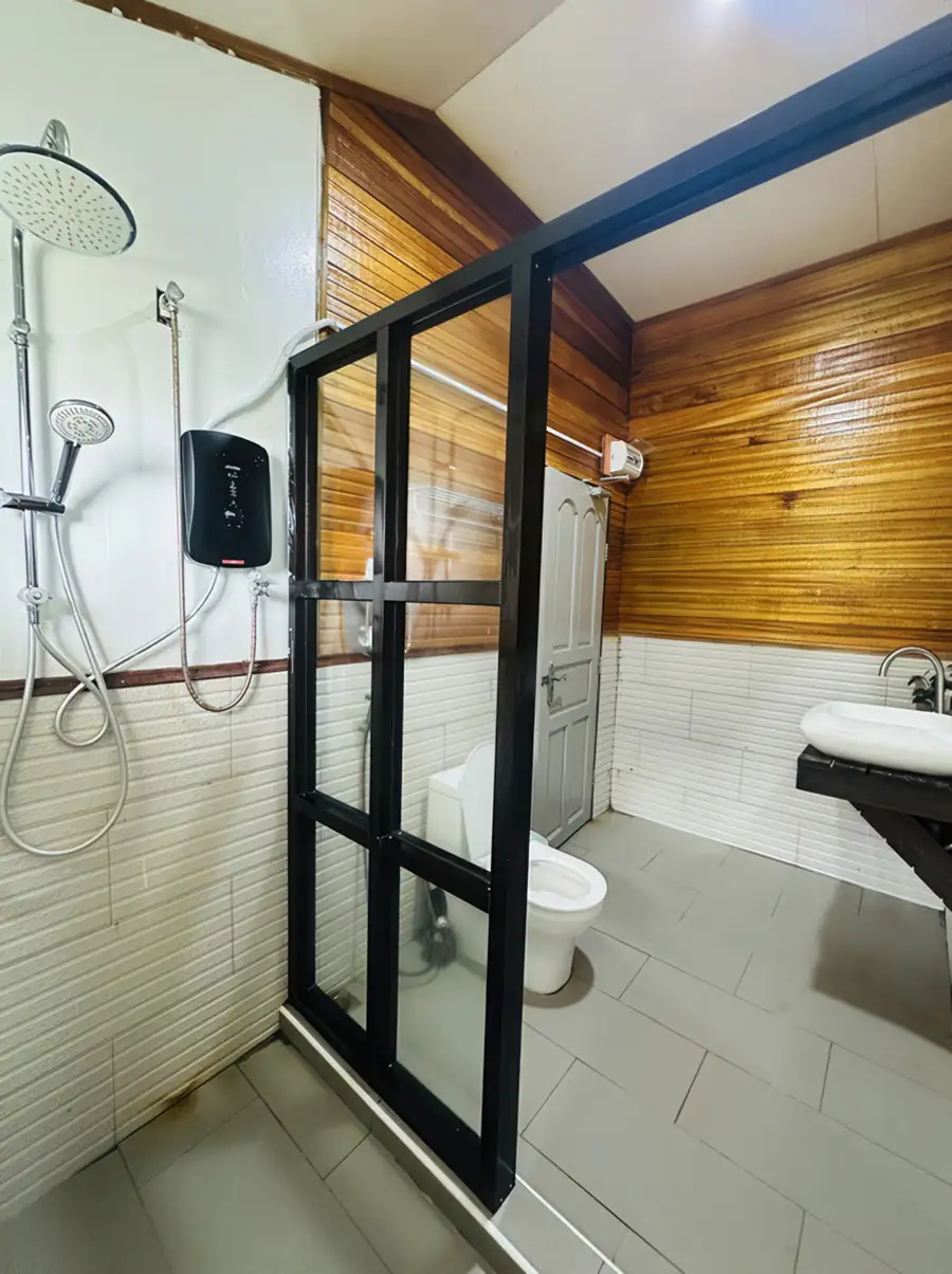A premium shower area at Dayang Resort focusing on a glass enclosure, elegant wood-patterned wall tiling, and a modern electric shower fixture.