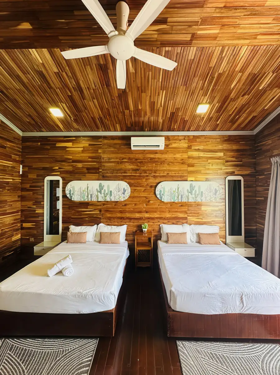 A symmetrical bedroom at Dayang Resort in the Islands of Semporna featuring two comfortable beds, modern cactus artwork, traditional style wood panel walls with polished teak floors, and A/C.